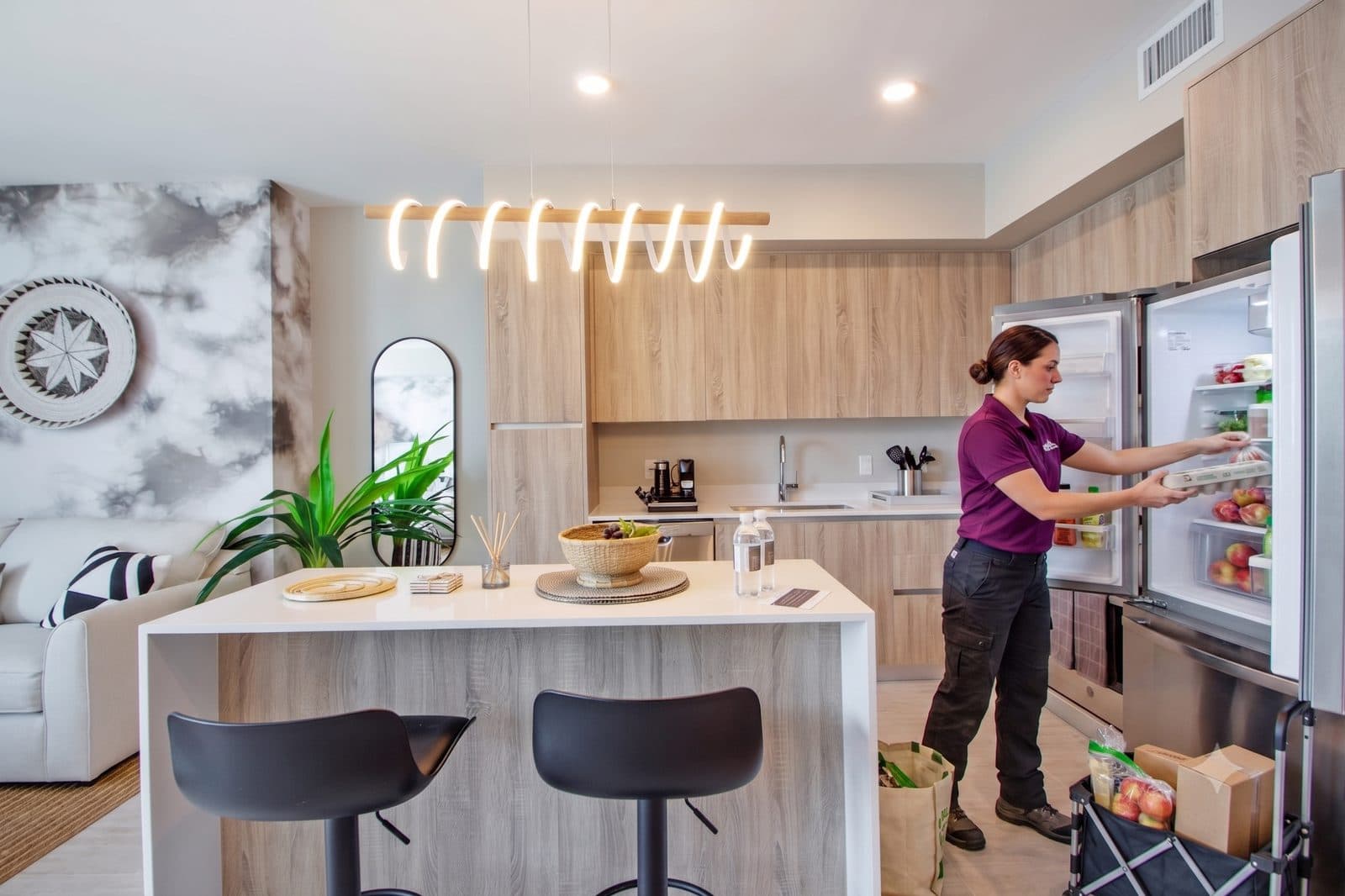 A RoomBox associate stocking the fridge of a condo-hotel kitchen before the guest arrives